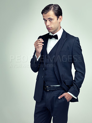 Buy stock photo Portrait, attitude or young gentleman smoking a cigarette in studio, confidence or vintage fashion by white background. Face, serious or man in retro suit or tuxedo, bow tie or classy at formal event