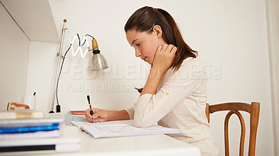 Buy stock photo Shot of a young woman studying at her desk at home