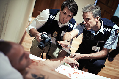 Buy stock photo Cropped shot of two police officers investigating a crimescene