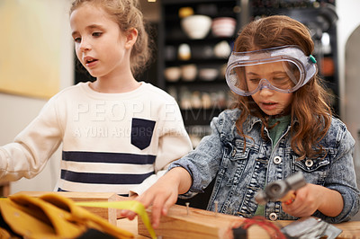 Buy stock photo Play, game and girls with construction, wood and learning with fun or education with hobby or creative. Child development, friends or kids with tools or bonding together with hammer or safety glasses