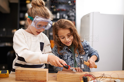 Buy stock photo Shot of two little girls busy at work on creating something with tools