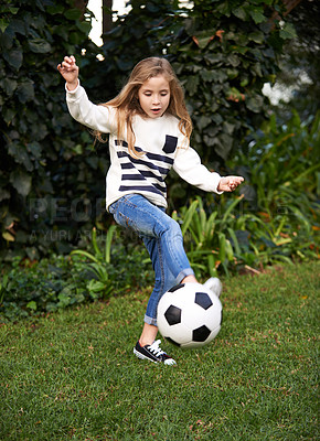 Buy stock photo Shot of a little girl playing with a soccer ball in a garden