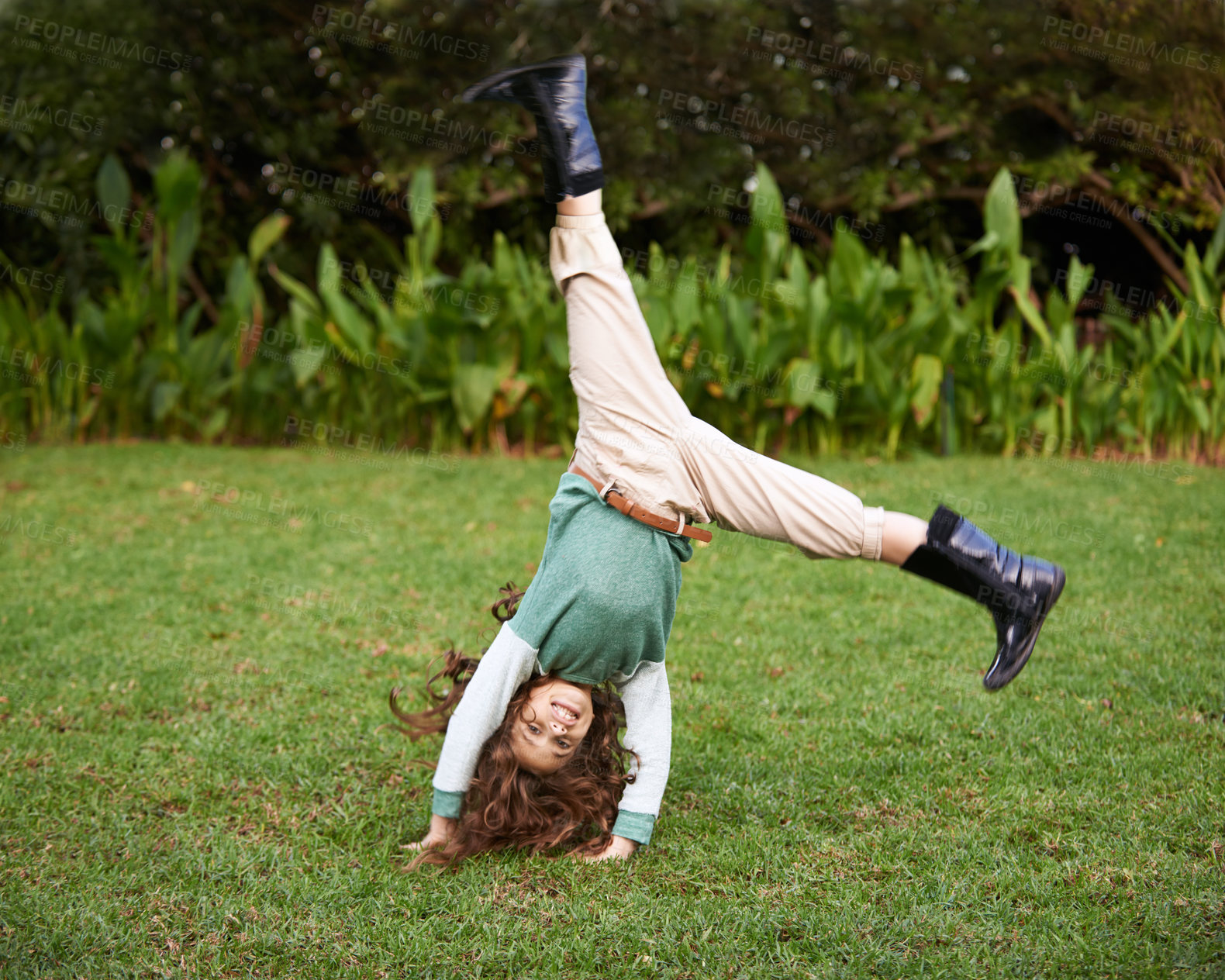 Buy stock photo Shot of a cute little girl doing cartwheels on the grass