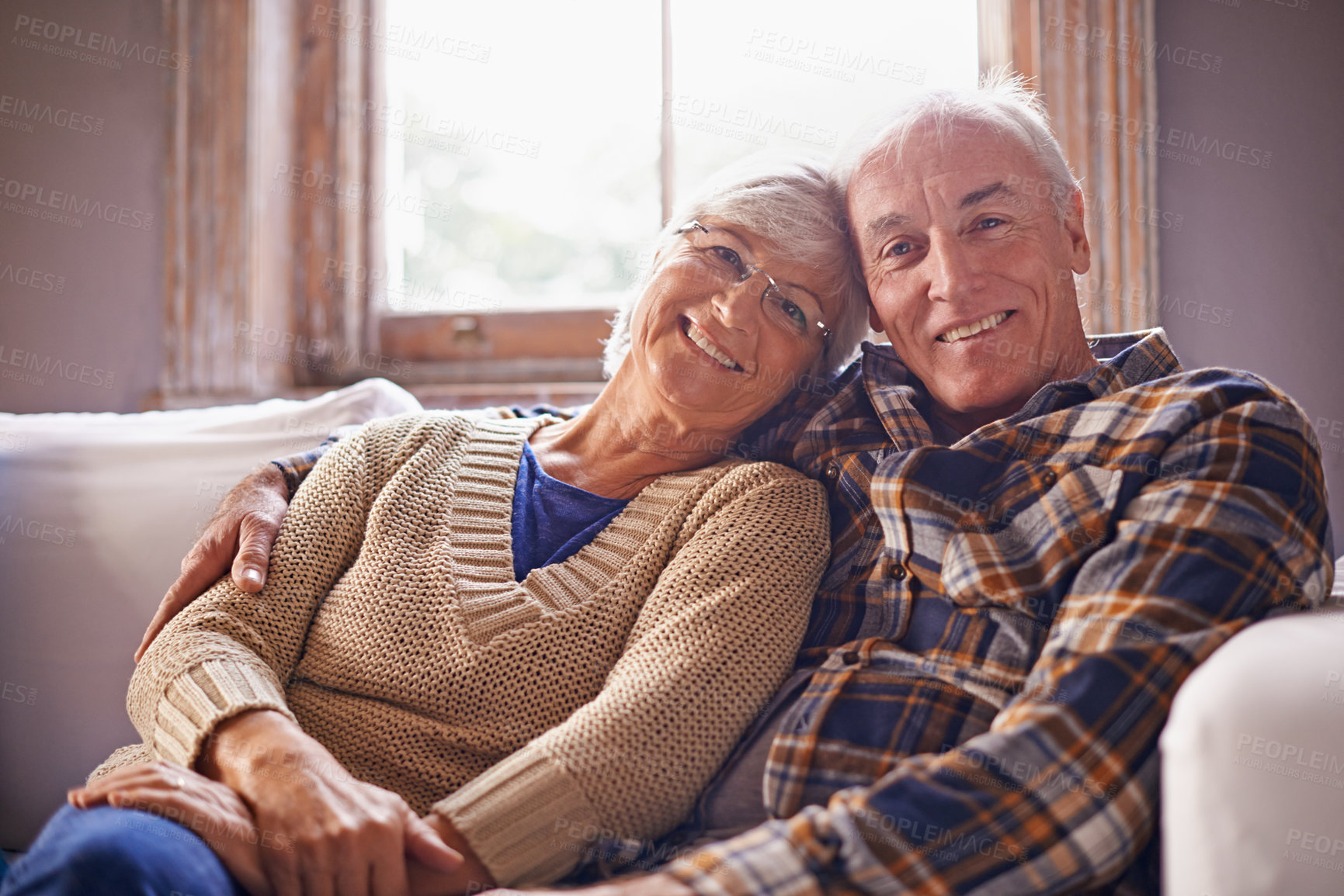 Buy stock photo A portrait of a happy senior couple sitting in their living room at home