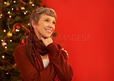 Buy stock photo A happy mature woman looking thoughtful in front of a Christmas tree