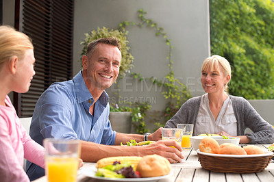 Buy stock photo A cropped shot of a happy family enjoying a meal together outdoors on a sunny day