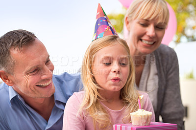 Buy stock photo Girl, blowing or candle at happy birthday, party or cake as fun wish, family or bonding together. Papa, mama or child or smile at celebration, congratulations or childhood growth and development