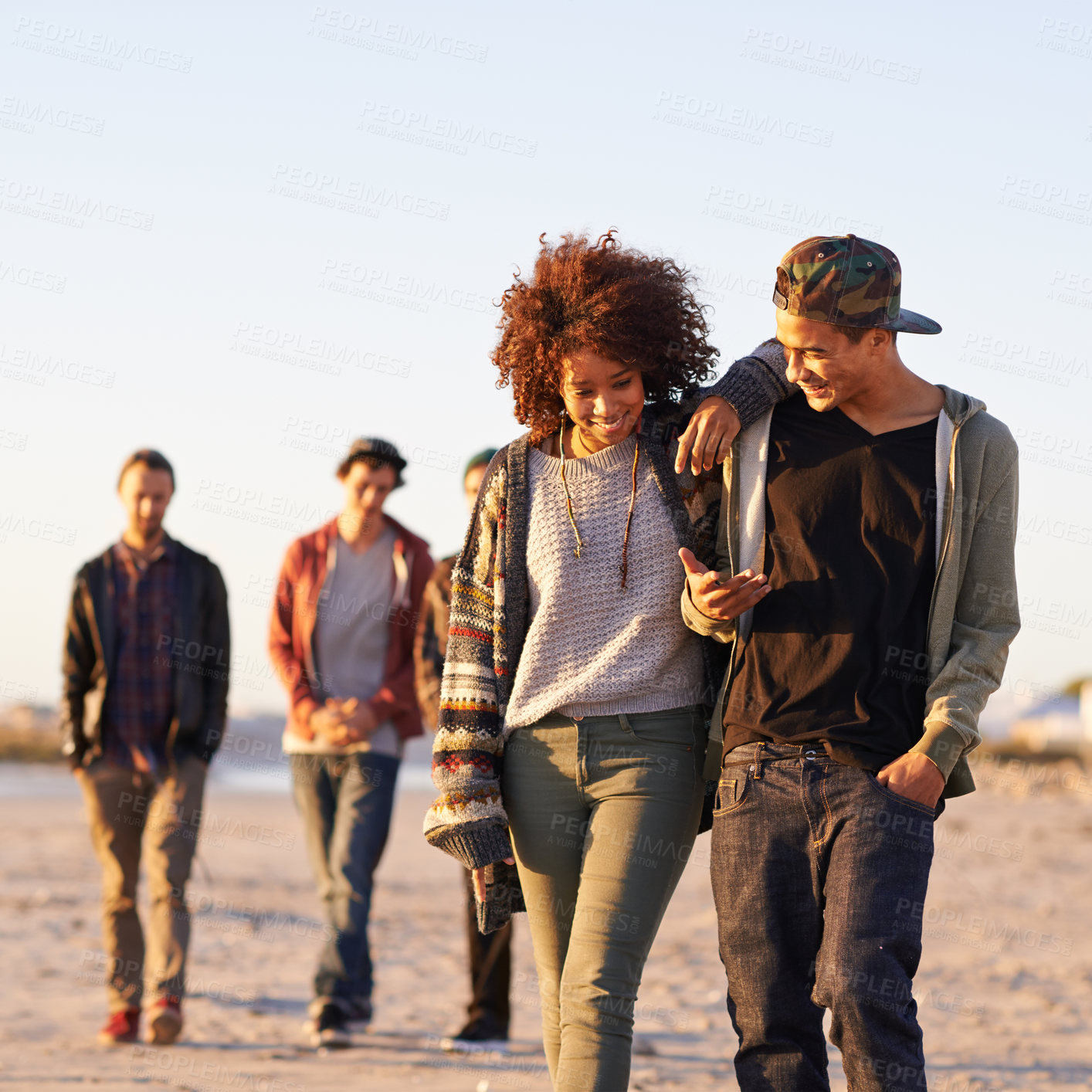 Buy stock photo Shot of a group of friends walking along a beach at sunset