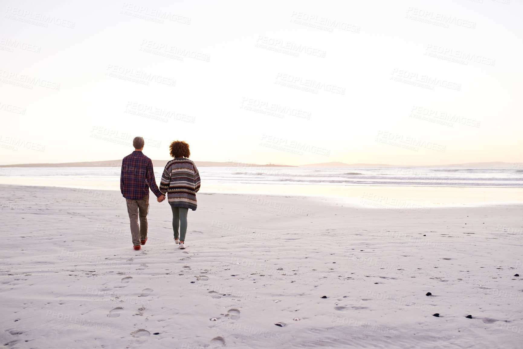 Buy stock photo Couple, sea and walking together holding hands, happy calm people on vacation. Ocean, outdoor and partners in love with respect and care, date and romantic stroll for relax with seaside sunrise
