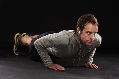 Buy stock photo Man, face and push up with fitness or music in studio with exercise, workout and training with earphones. Athlete, person and bodybuilder on floor with audio, radio and podcast on black background
