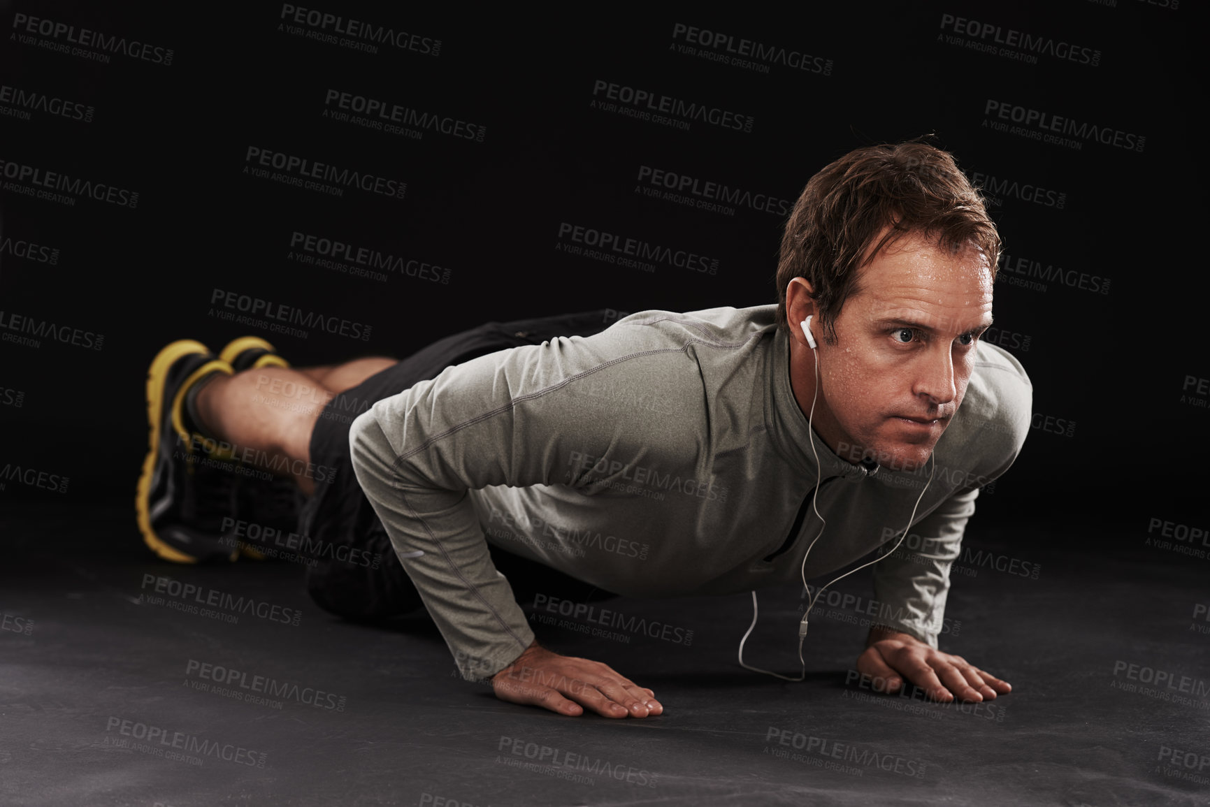 Buy stock photo Man, face and push up with fitness or music in studio with exercise, workout and training with earphones. Athlete, person and bodybuilder on floor with audio, radio and podcast on black background