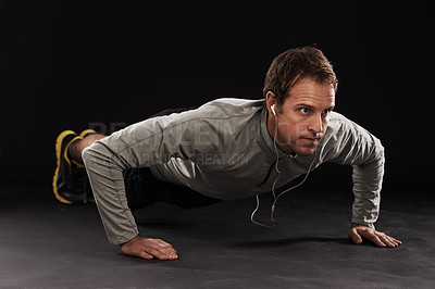 Buy stock photo Man, face and push up with workout or music in studio with exercise, fitness and training with earphones. Athlete, person and bodybuilder on floor with audio, radio and podcast on black background