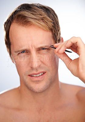 Buy stock photo Cropped studio shot of a man wincing in pain while plucking his eyebrows