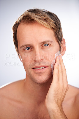Buy stock photo Studio shot of a handsome man applying moisturiser