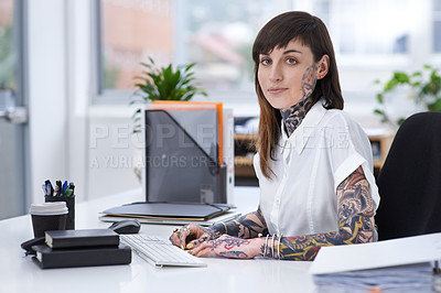 Buy stock photo A shot of a tattooed businesswoman sitting at her desk in her office