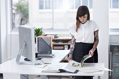 Buy stock photo Shot of a gorgeous young tattooed businesswoman flipping through a document