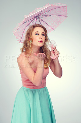 Buy stock photo Shot of a cute blonde girl blowing a kiss while holding a pink parasol