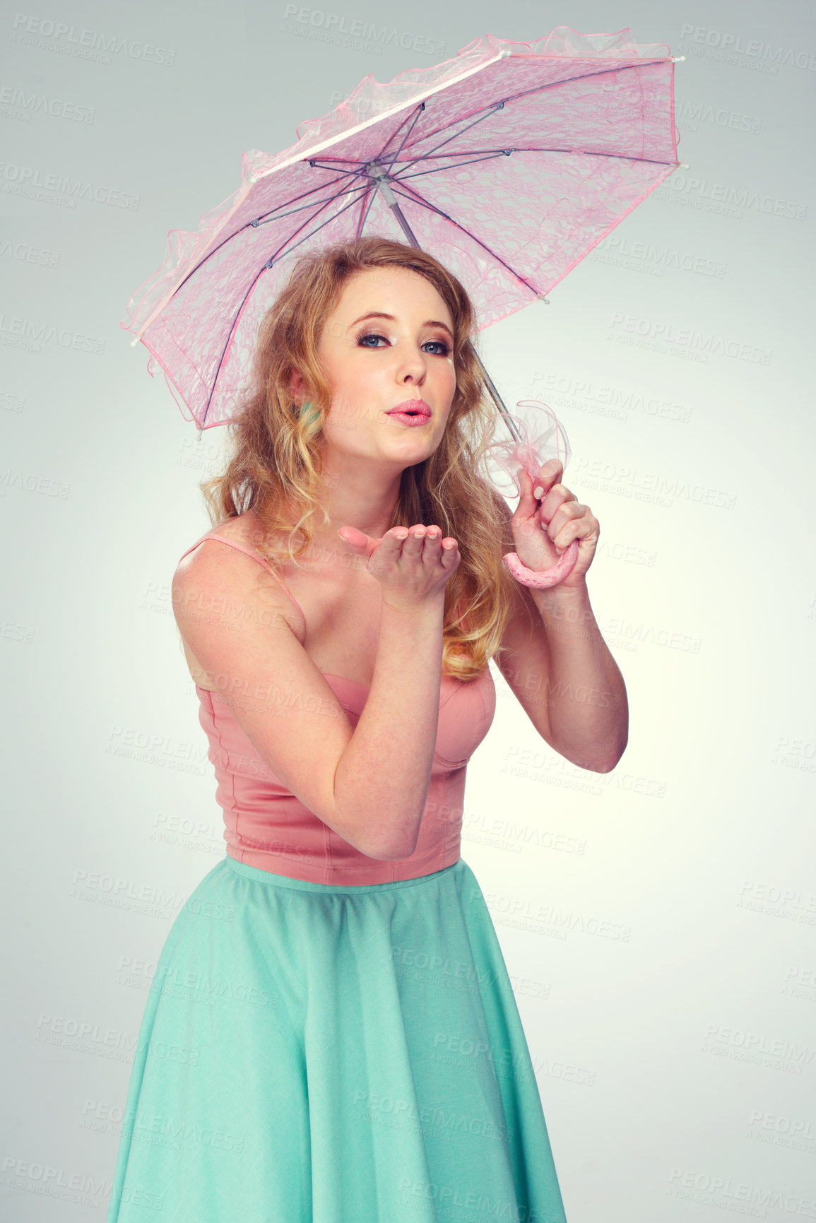 Buy stock photo Shot of a cute blonde girl blowing a kiss while holding a pink parasol