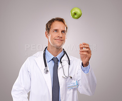 Buy stock photo Man, doctor and apple for healthcare in studio, medical expert and dietician on gray background. Male person, fruit and proud of choice or decision for nutrition, vitamins and minerals for health