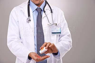Buy stock photo Cropped shot of a doctor emptying a bottle of pills into his hand