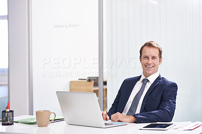 Buy stock photo Portrait of a handsome young businessman sitting at his desk with his laptop