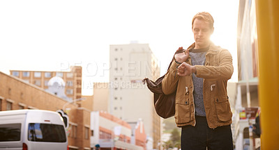 Buy stock photo Cropped shot of a young man in the city looking at his watch
