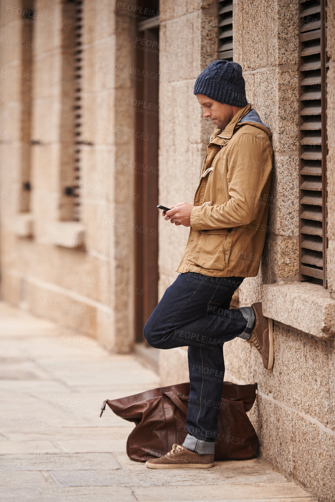 Buy stock photo Full length shot of a fashionable man using his mobile phone in the city