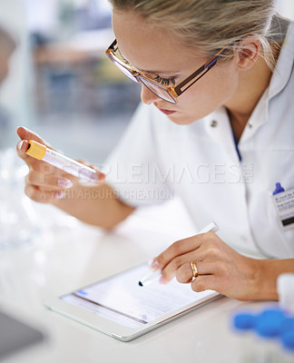 Buy stock photo A young scientist recording her findings on a tablet