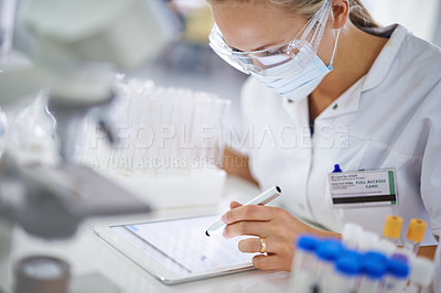 Buy stock photo A young researcher recording her findings on a tablet in the lab