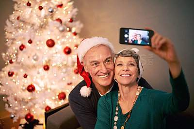 Buy stock photo Christmas, selfie and senior couple with love, holiday and support in home with social media. Happy, retirement and marriage with smile and profile picture in house with celebration and santa hat
