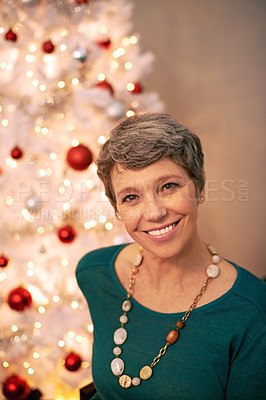Buy stock photo Cropped portrait of a happy mature woman sitting in front of her Christmas tree
