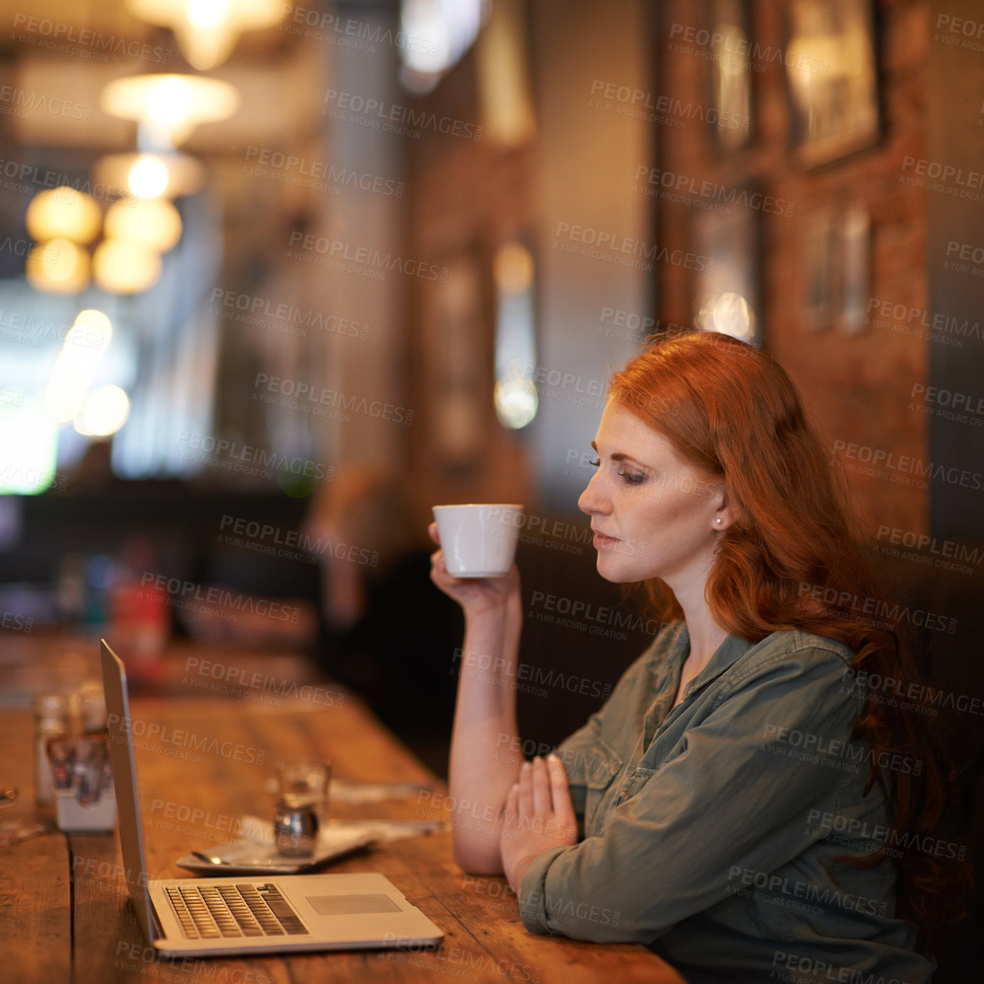 Buy stock photo Cropped shot of a young woman sitting with her laptop at a coffee shop