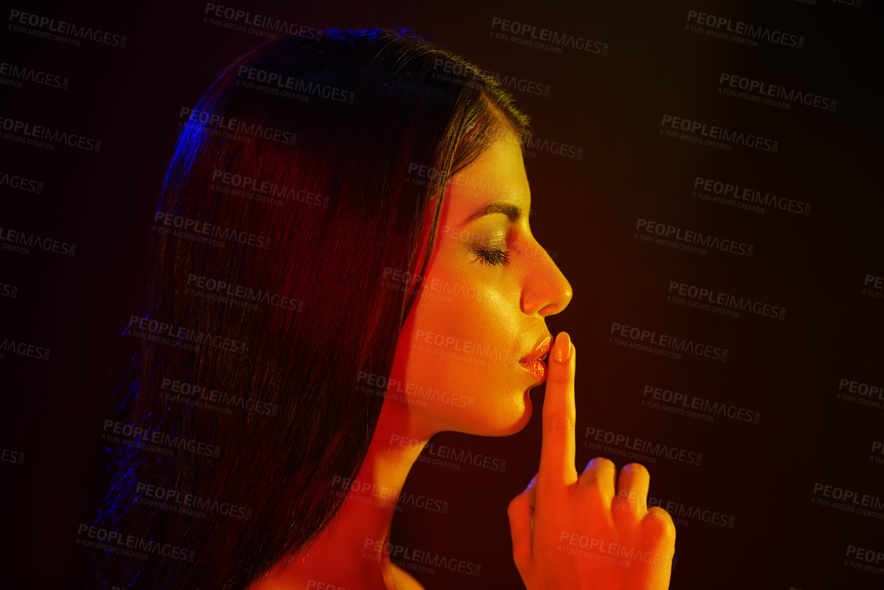 Buy stock photo Studio shot of a beautiful young woman with her finger on her lips in artistic lighting