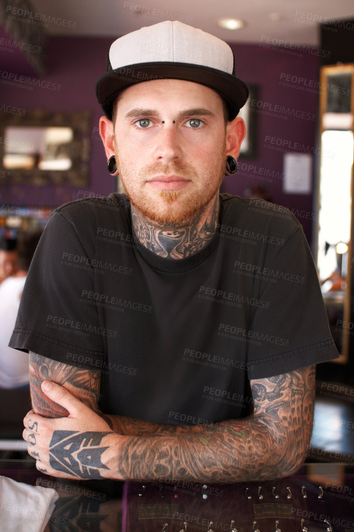 Buy stock photo Tattoos, creative and portrait of a man with tattoos standing by the counter of his artistic studio. Confident, cool and punk man with a edgy, funky and body art or ink creativity business store.