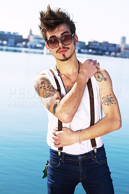 Buy stock photo Sunglasses, portrait and serious man by sea with stylish tattoo, body art and fashion. Punk, ocean and trendy male person standing outdoor in Spain with cool clothes, attitude and aesthetic mockup.