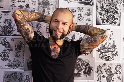 Buy stock photo Tattoos, creativity and portrait of a male artist standing by sketches or drawings in his studio. Happy, smile and face of a punk man with a edgy, funky and body art or ink creative business store.