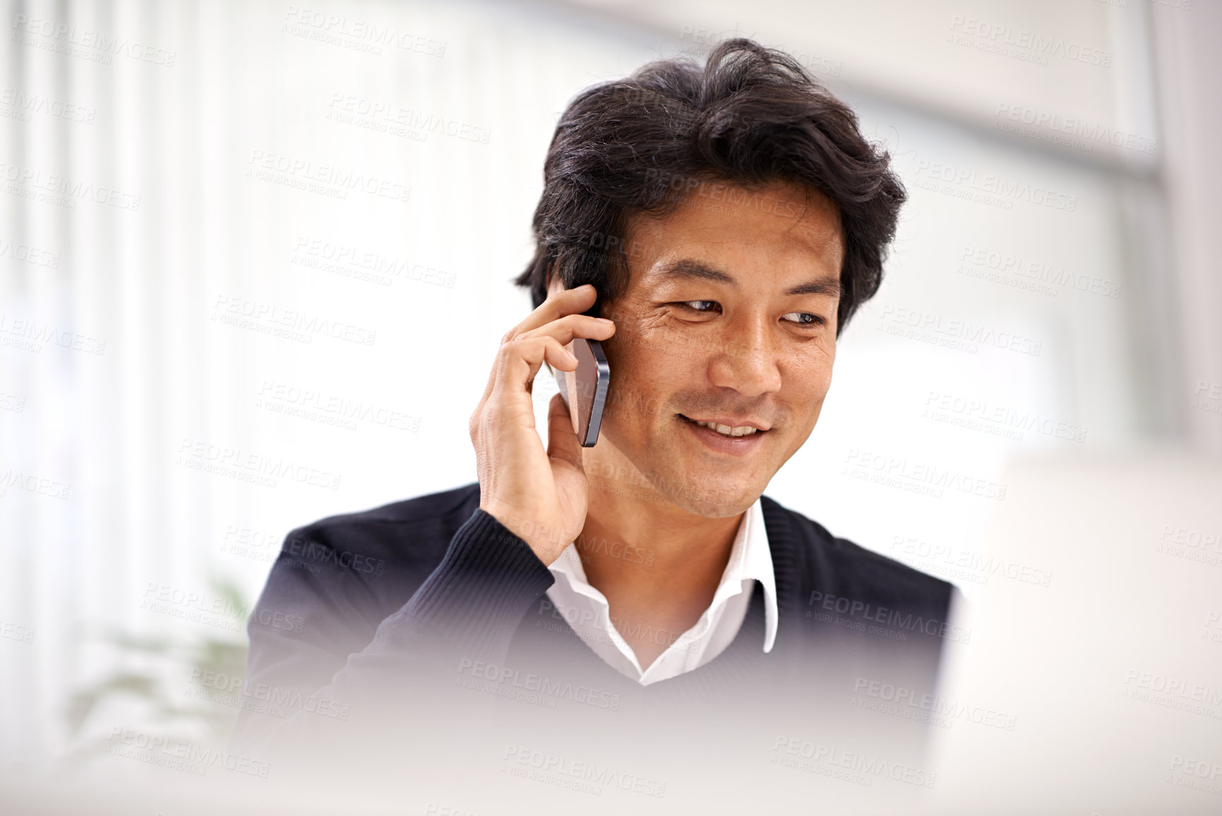 Buy stock photo Shot of a handsome asian businessman on the phone while working at his desk