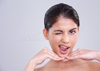 Buy stock photo Happy woman, portrait and wink with skincare in satisfaction for beauty, cosmetics or facial treatment on a gray studio background. Face of female person, brunette or model with smile on mockup space