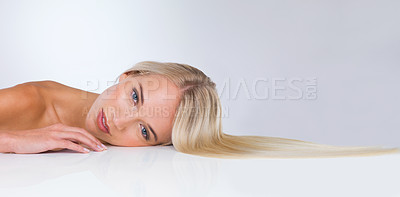 Buy stock photo A cropped studio shot of a beautiful young woman lying down against a gray background