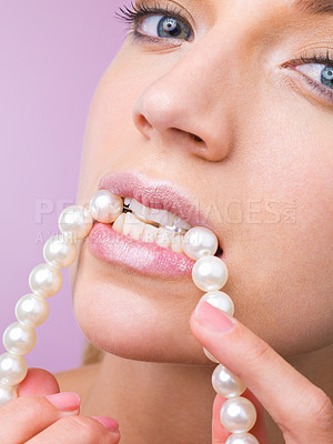 Buy stock photo Woman, studio and bite pearl necklace in portrait for beauty, cosmetic or closeup by purple background. Girl, person and model with jewelry for wellness with facial skincare, makeup or transformation