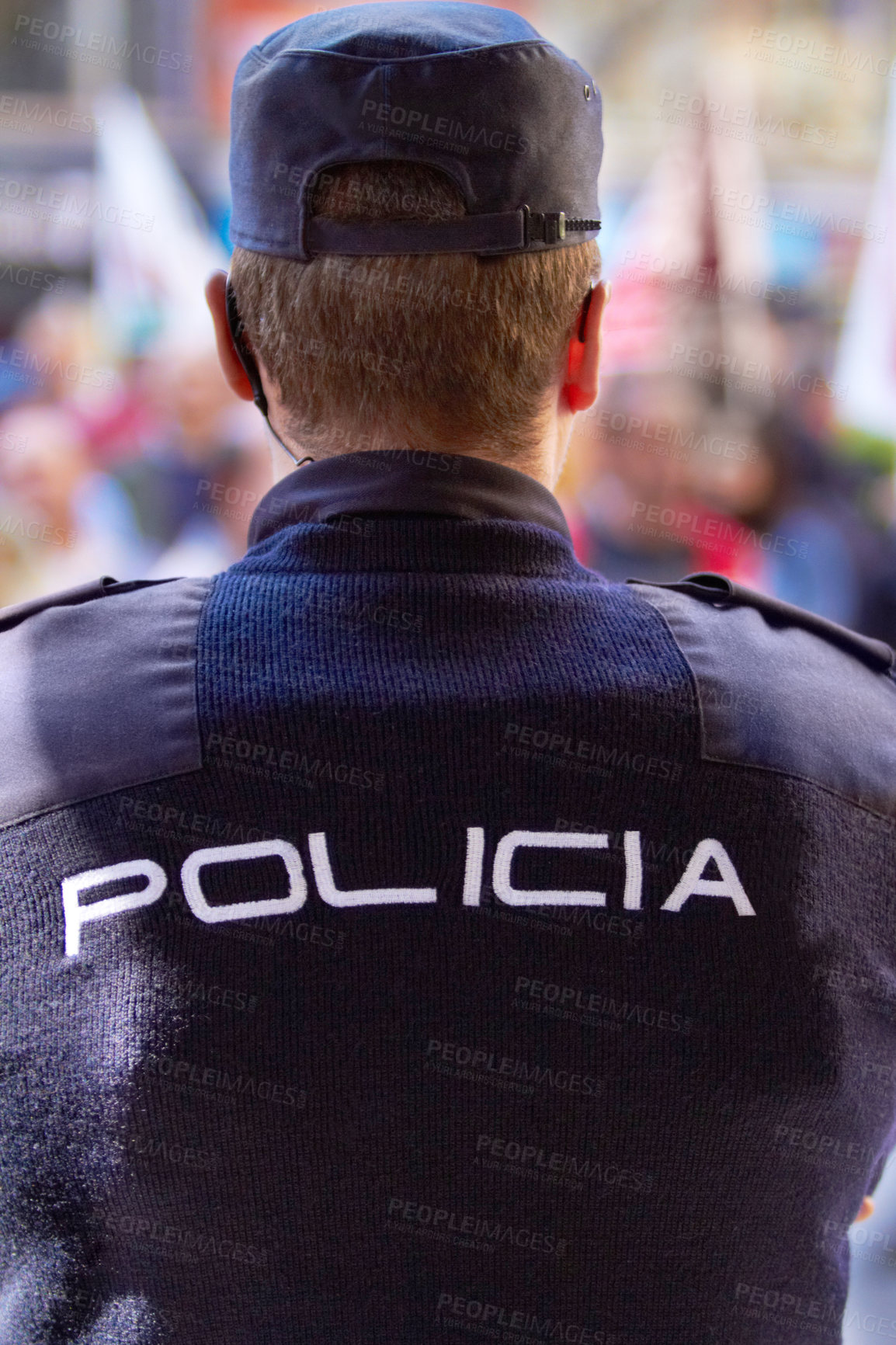 Buy stock photo Rearview shot of a policeman wearing a uniform with the word, "POLICIA" on the back