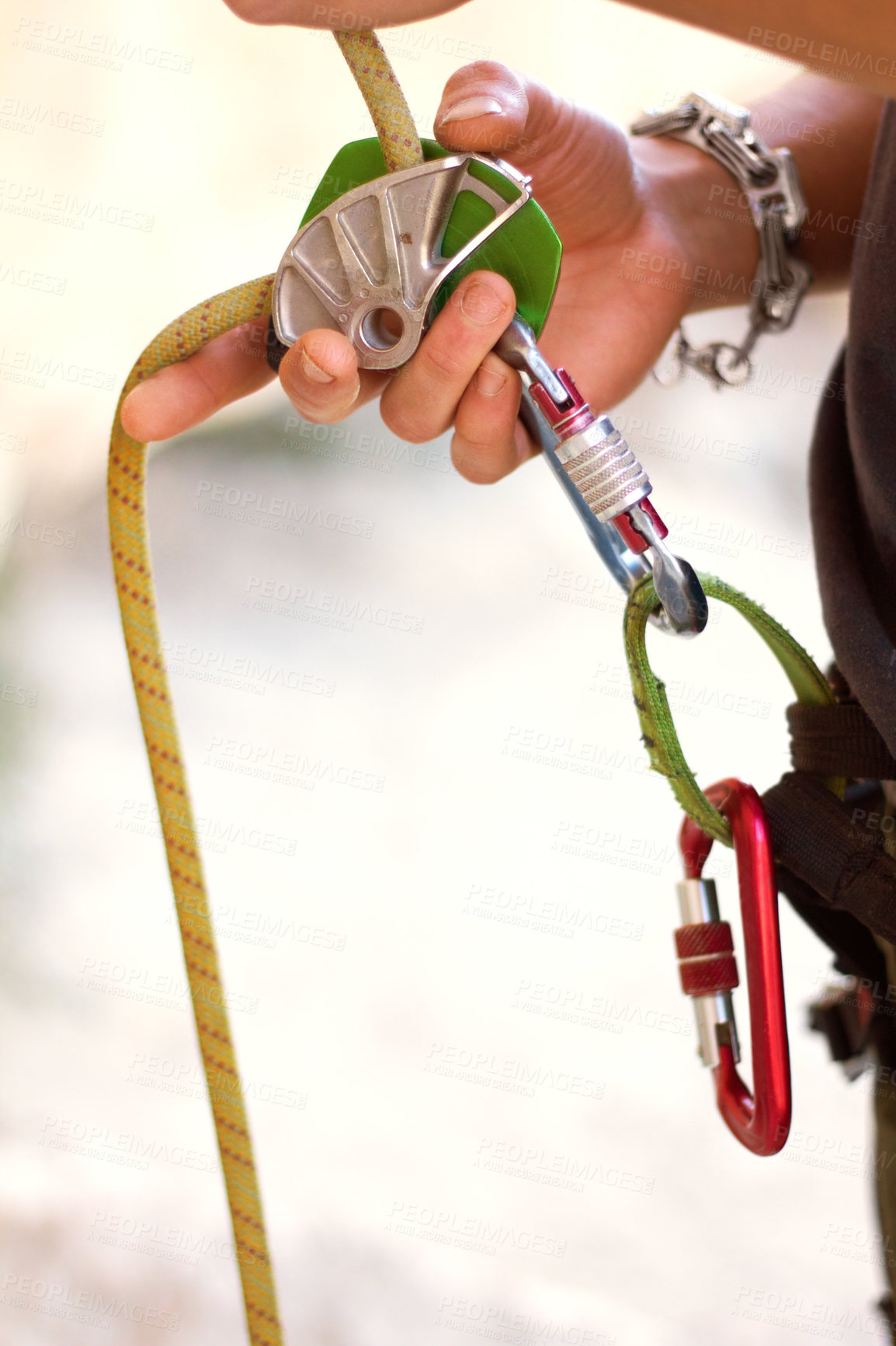 Buy stock photo Cropped shot of a young rock climber standing and adjusting his harnesses