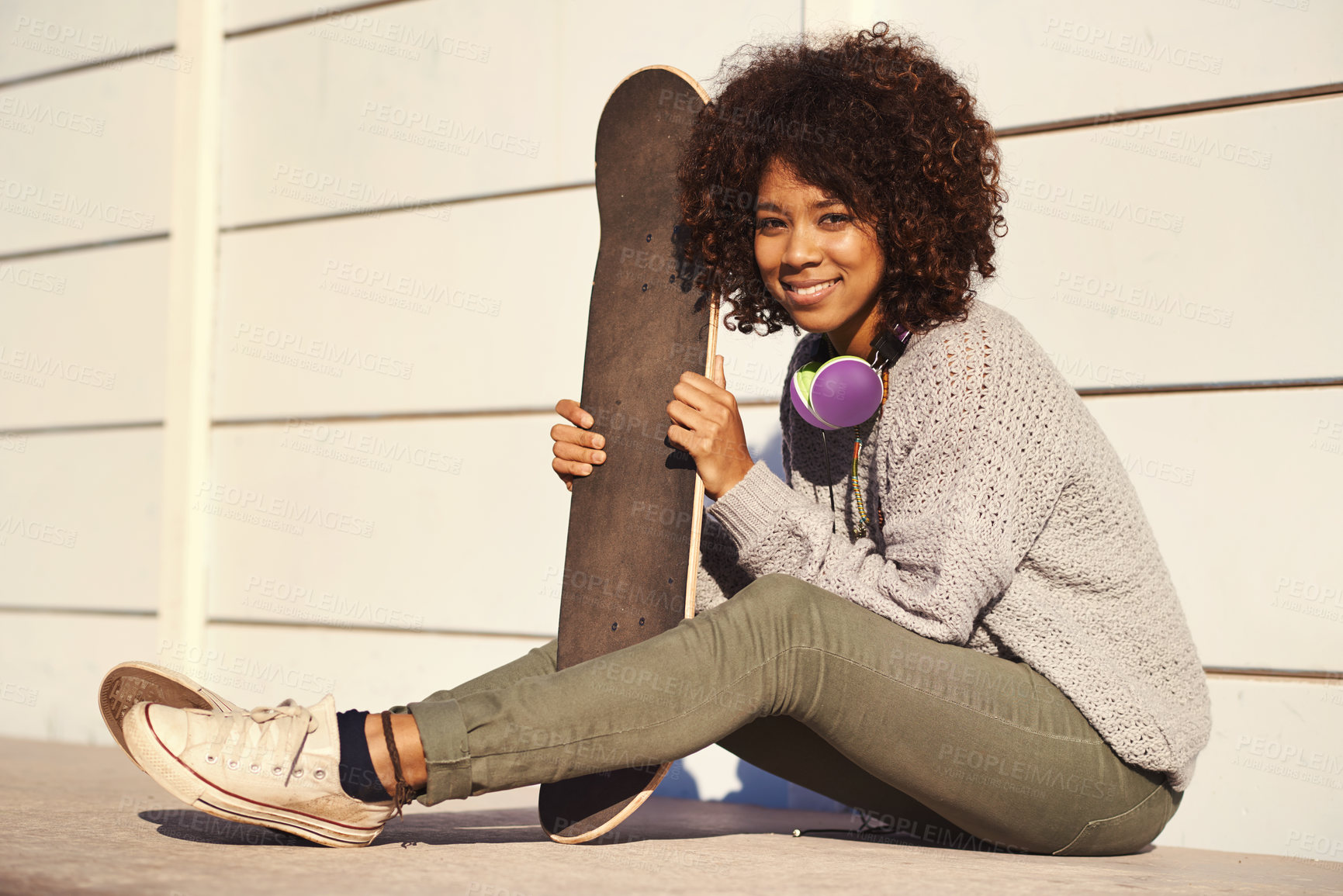 Buy stock photo Portrait, smile and woman with skateboard in city by wall in summer for sport, fashion or relax outdoor. Happy person, skate park and gen z girl in casual clothes with headphones in South Africa