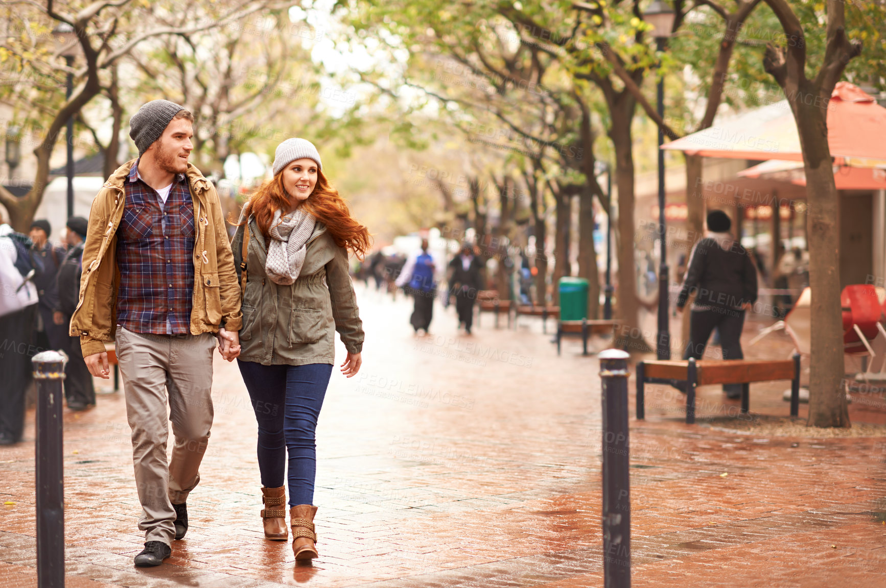 Buy stock photo Shot of a happy young couple walking through an urban area together