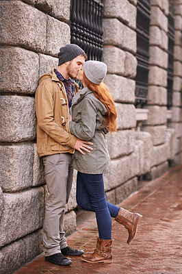 Buy stock photo Couple, love and kiss with affection outdoor at sidewalk or against wall in cold weather, together and support in London. Relationship, date and bonding for romance with commitment, care and happy