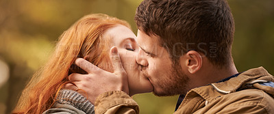 Buy stock photo Shot of a happy young couple sharing a kiss outdoors