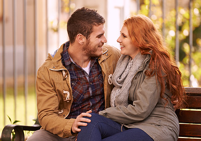Buy stock photo Couple, smile and sit on bench at park with affection in cold weather or winter, together and support in London. Relationship, commitment and bonding for romance with soulmate, care and happiness