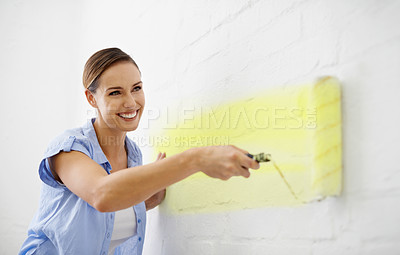 Buy stock photo Shot of an attractive female painting her wall with a paint roller