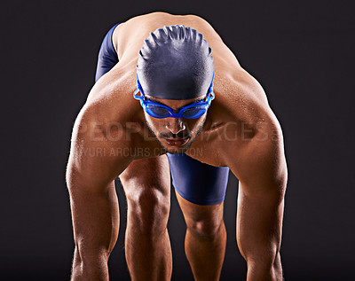 Buy stock photo Studio shot of a handsome swimmer ready to dive off the starting block