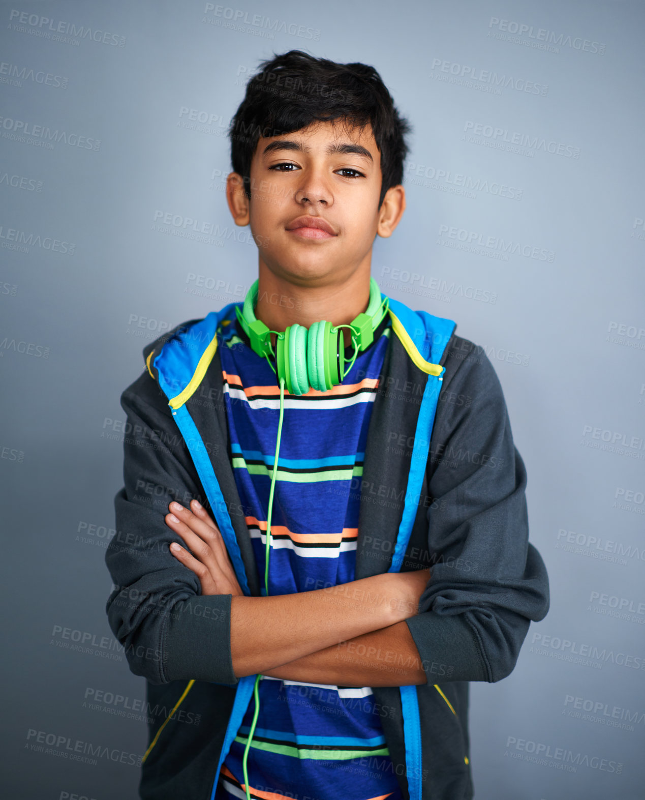 Buy stock photo Studio shot of a young boy looking serious with headphones around his neck